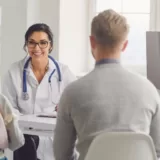 A smiling female doctor in a white coat, warmly engaging with a family during a medical consultation