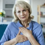 An older adult female touching her chest showing some discomfort