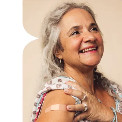 woman smiling with a vaccine bandage in her arm